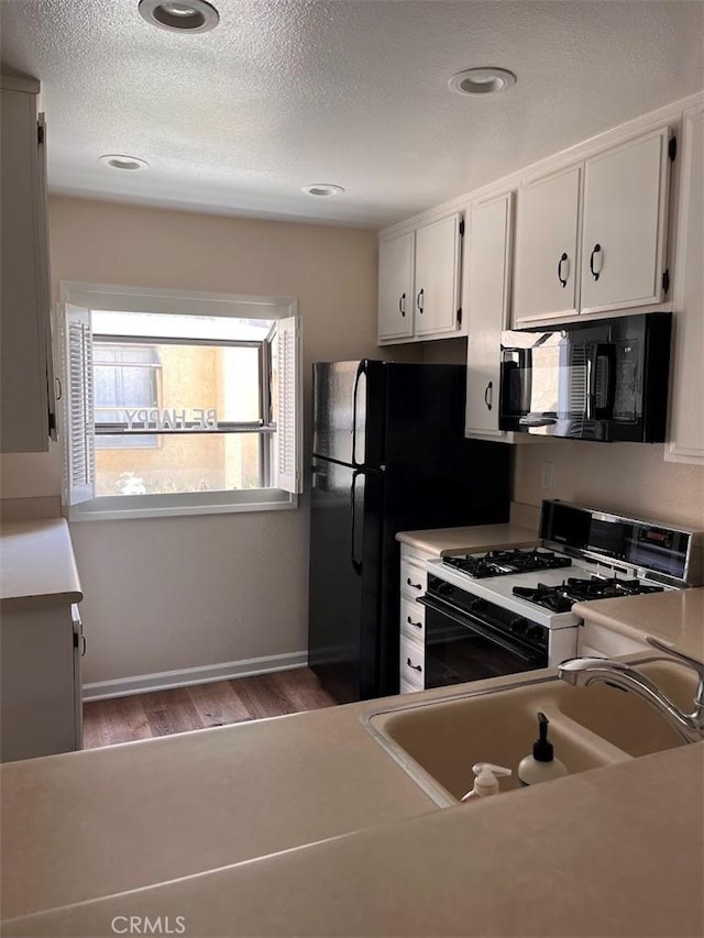 12750 Centralia St Unit 142, Lakewood, CA 90715 - kitchen with wood finished floors, a sink, black appliances, light countertops, and white cabinets