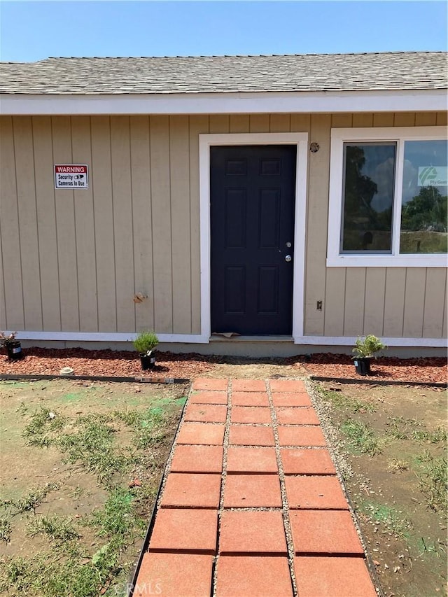 property entrance featuring roof with shingles