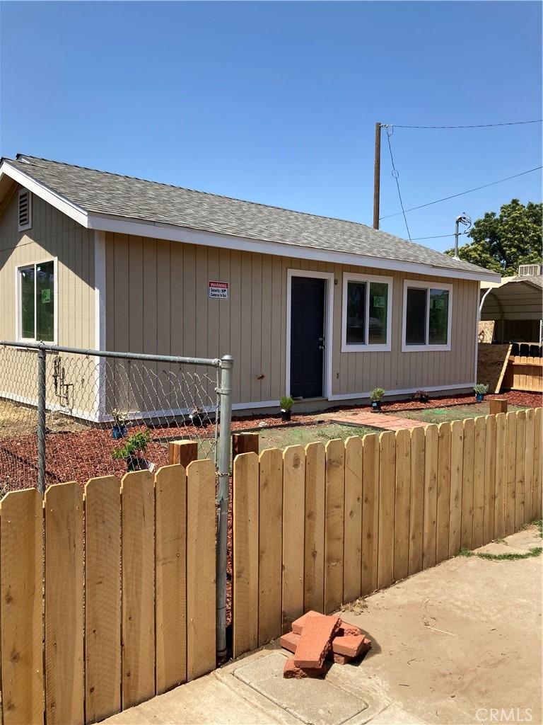view of front of property featuring fence, a gate, and roof with shingles