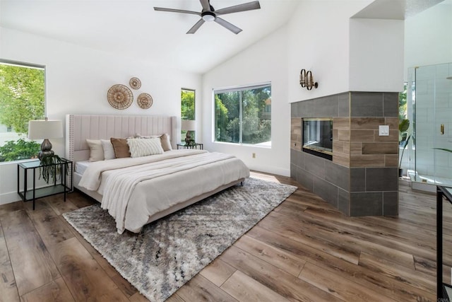 bedroom with wood-type flooring, multiple windows, and a tile fireplace