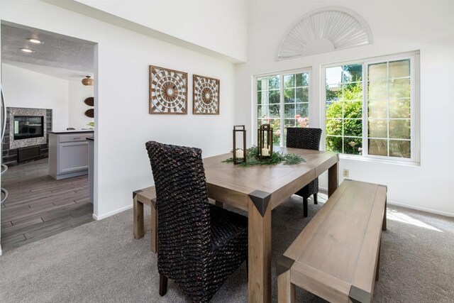 dining room featuring baseboards, a fireplace, and light carpet