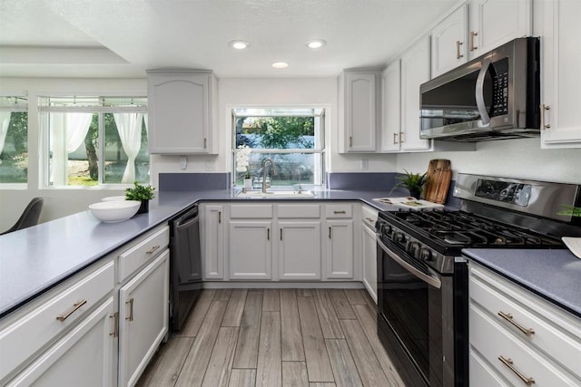 kitchen featuring a sink, light wood finished floors, stainless steel appliances, recessed lighting, and white cabinetry