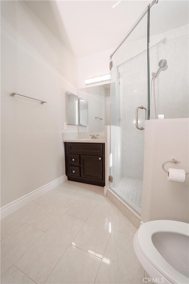 bathroom featuring tile patterned flooring, a stall shower, vanity, baseboards, and toilet