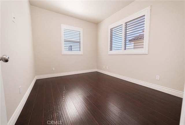 unfurnished room featuring baseboards and dark wood finished floors