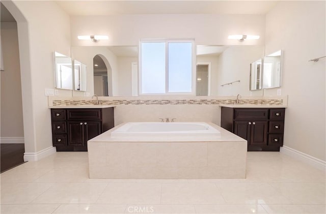 full bath featuring a sink, baseboards, tile patterned flooring, and a garden tub