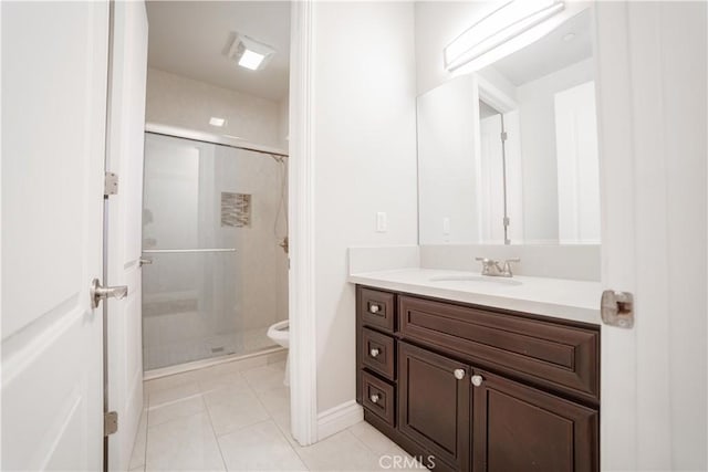 bathroom with a stall shower, vanity, tile patterned floors, baseboards, and toilet