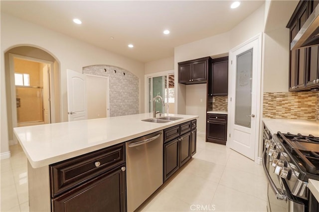 kitchen featuring ventilation hood, backsplash, appliances with stainless steel finishes, and a sink