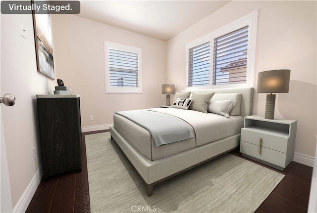 bedroom featuring baseboards, multiple windows, and wood finished floors