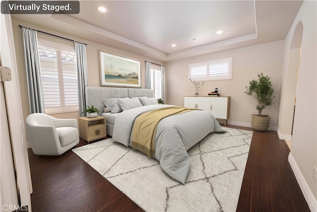 bedroom featuring wood-type flooring, a raised ceiling, and baseboards