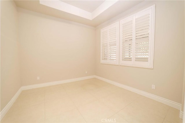 unfurnished room with light tile patterned flooring, baseboards, and a tray ceiling