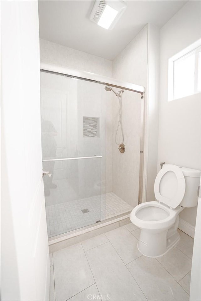 bathroom featuring toilet, a shower stall, and tile patterned flooring