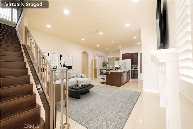 living room featuring recessed lighting, arched walkways, stairs, and light tile patterned floors