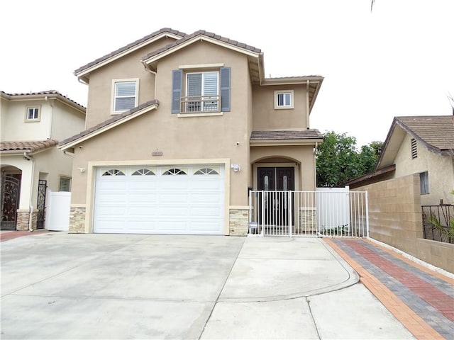 view of front of house featuring a tiled roof, fence, concrete driveway, an attached garage, and stucco siding
