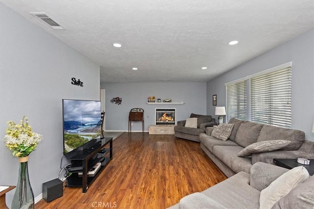 living area featuring baseboards, wood finished floors, visible vents, and recessed lighting
