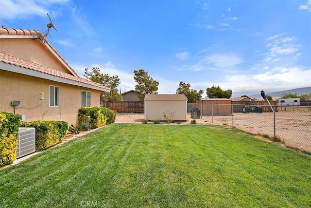 view of yard with a fenced backyard, an outdoor structure, and central AC