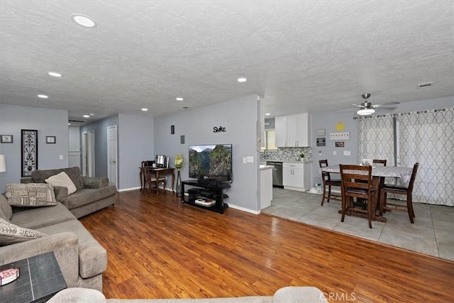 living room featuring a ceiling fan, a textured ceiling, light wood finished floors, and recessed lighting
