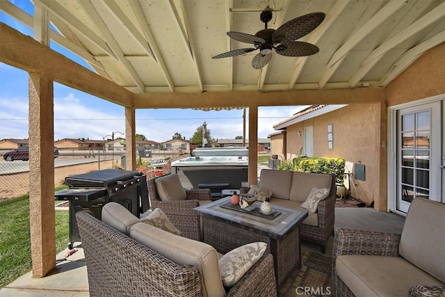 view of patio with outdoor lounge area, fence, a residential view, ceiling fan, and a hot tub