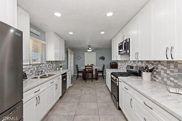 kitchen with a ceiling fan, a sink, tasteful backsplash, appliances with stainless steel finishes, and white cabinetry