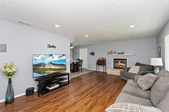 living area with recessed lighting, wood finished floors, visible vents, baseboards, and a glass covered fireplace