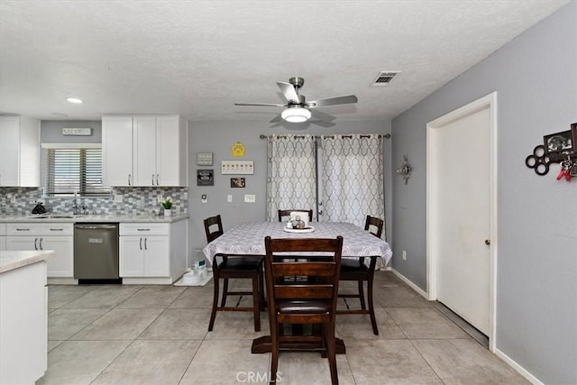 dining room with a textured ceiling, baseboards, visible vents, ceiling fan, and light tile patterned floors