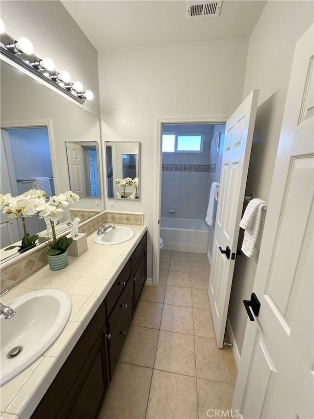 bathroom featuring a sink, tile patterned flooring, double vanity, and visible vents
