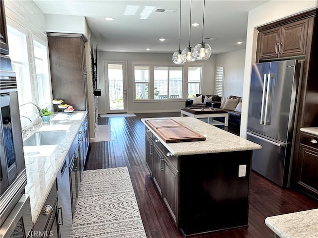 kitchen with visible vents, a kitchen island, high end fridge, open floor plan, and dark wood-type flooring