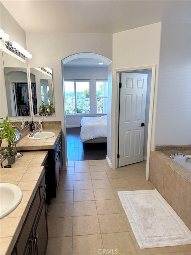 ensuite bathroom with vanity, ensuite bath, tile patterned floors, and a relaxing tiled tub