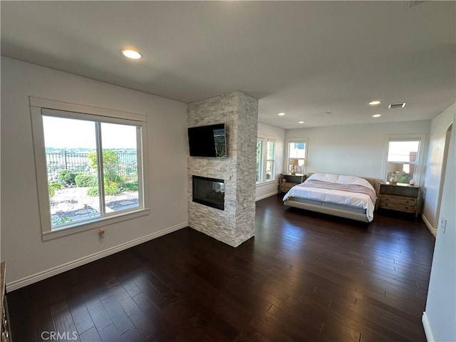 bedroom featuring visible vents, baseboards, a stone fireplace, dark wood-style floors, and recessed lighting