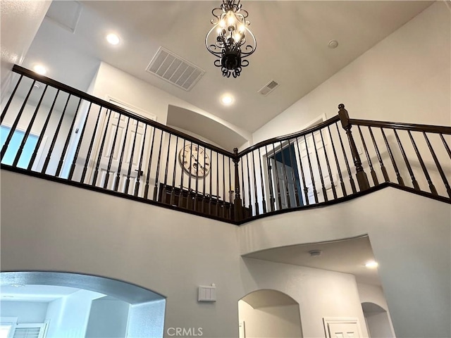 staircase featuring high vaulted ceiling, arched walkways, recessed lighting, and visible vents