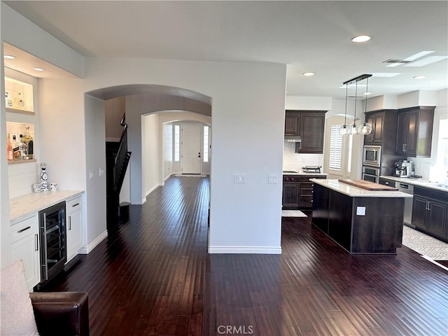 34036 Galleron St, Temecula, CA 92592 - kitchen with wine cooler, stainless steel appliances, arched walkways, dark wood-style floors, and recessed lighting