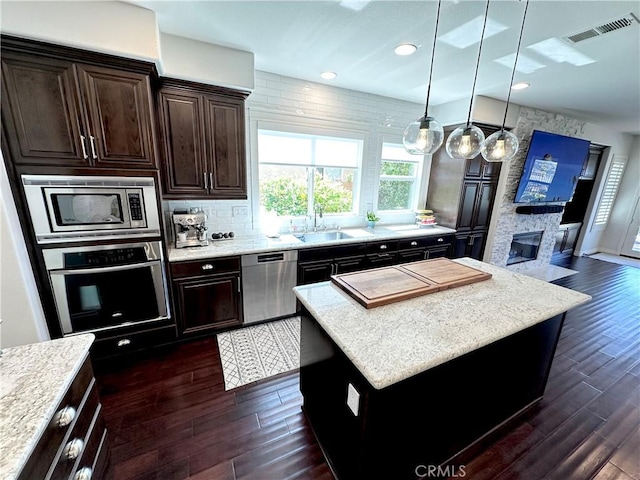 kitchen with visible vents, a fireplace, dark wood-style floors, a sink, and stainless steel appliances