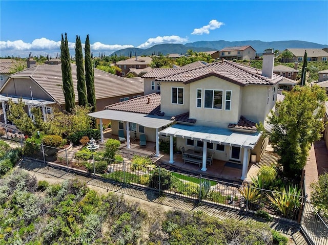 rear view of property featuring a patio, a tile roof, a mountain view, and a fenced backyard