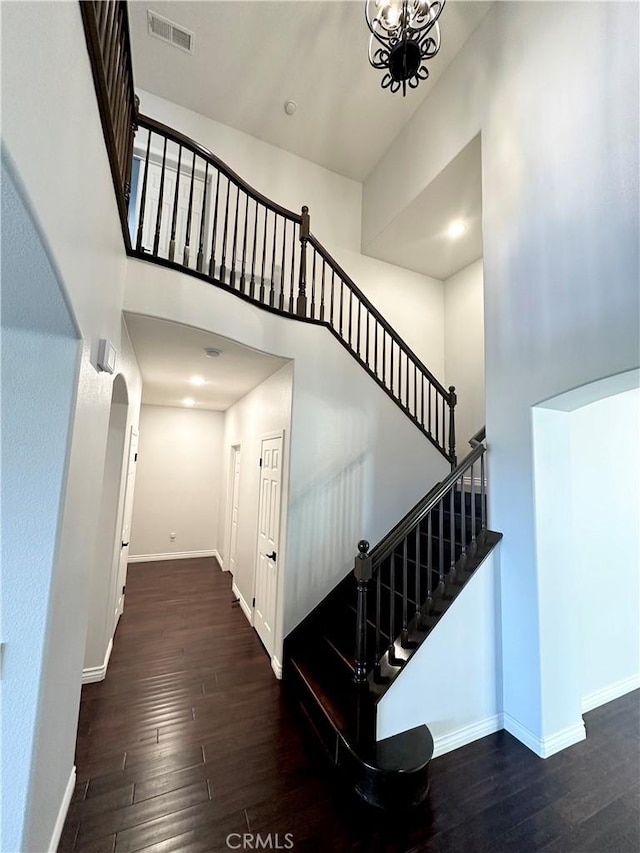 stairway with baseboards, a high ceiling, wood-type flooring, and visible vents