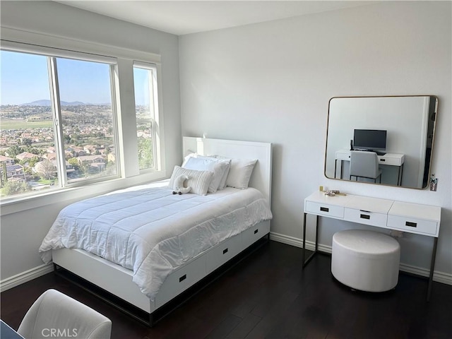 bedroom with baseboards, multiple windows, a mountain view, and dark wood-style flooring