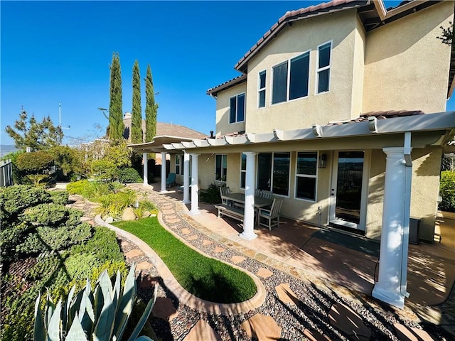 back of house featuring a patio area, stucco siding, a pergola, and a tile roof