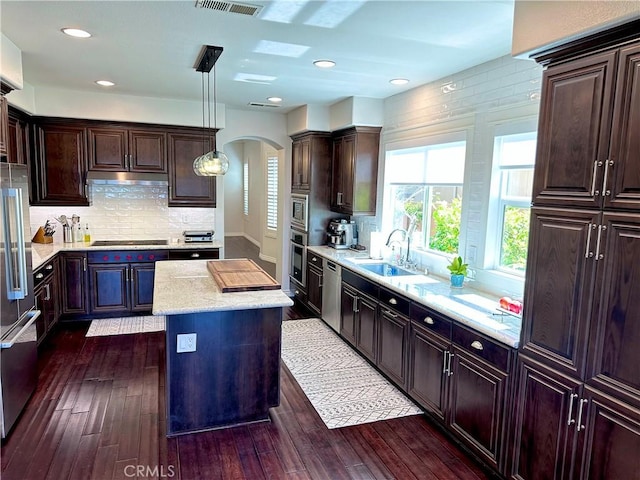 34036 Galleron St, Temecula, CA 92592 - kitchen with appliances with stainless steel finishes, arched walkways, dark wood-style flooring, a center island, and decorative backsplash