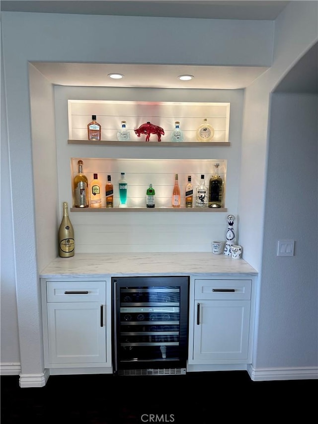 bar featuring beverage cooler, baseboards, and a bar