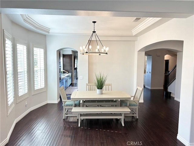 dining space featuring visible vents, arched walkways, wood-type flooring, an inviting chandelier, and ornamental molding