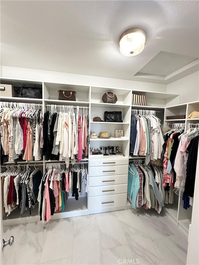 walk in closet featuring marble finish floor