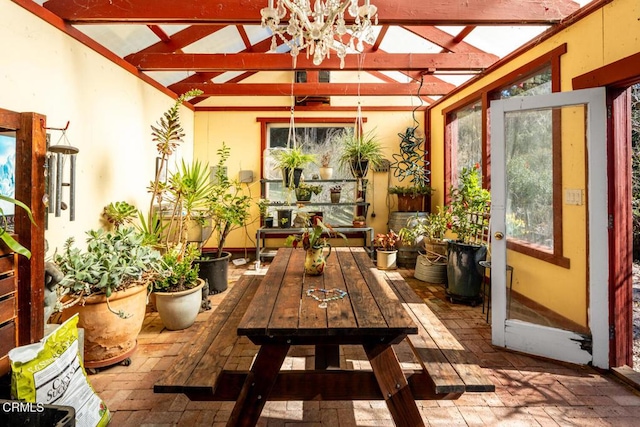 sunroom / solarium with a chandelier and beamed ceiling