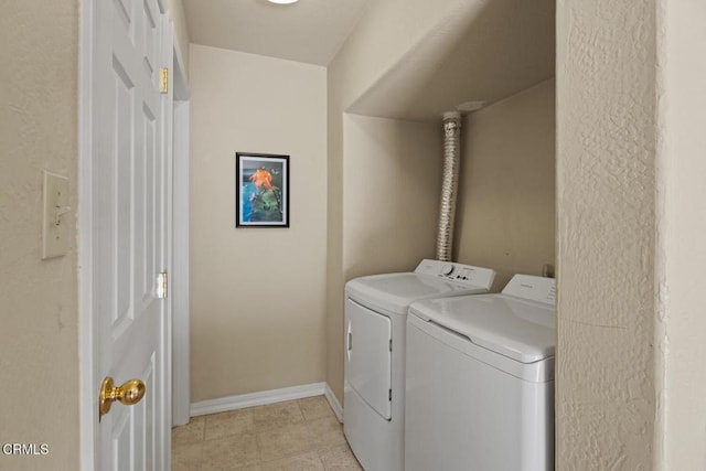 washroom featuring light tile patterned floors, washer and clothes dryer, laundry area, and baseboards