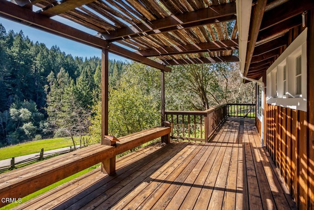 wooden deck featuring a wooded view and a pergola