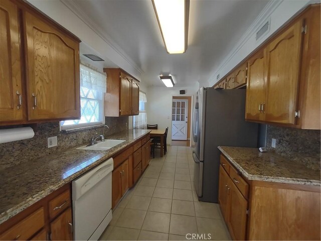 kitchen with dishwasher, brown cabinets, a sink, and light tile patterned floors