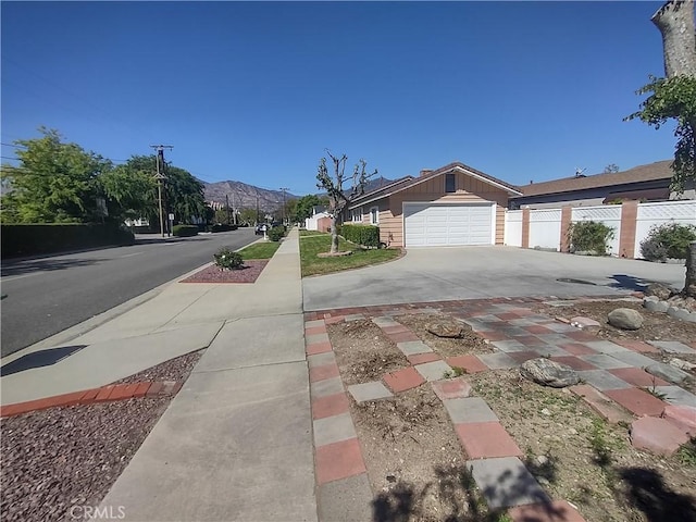 view of front facade featuring a garage, concrete driveway, fence, and a mountain view