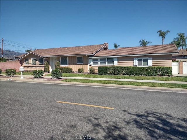 single story home with board and batten siding, a tiled roof, and fence