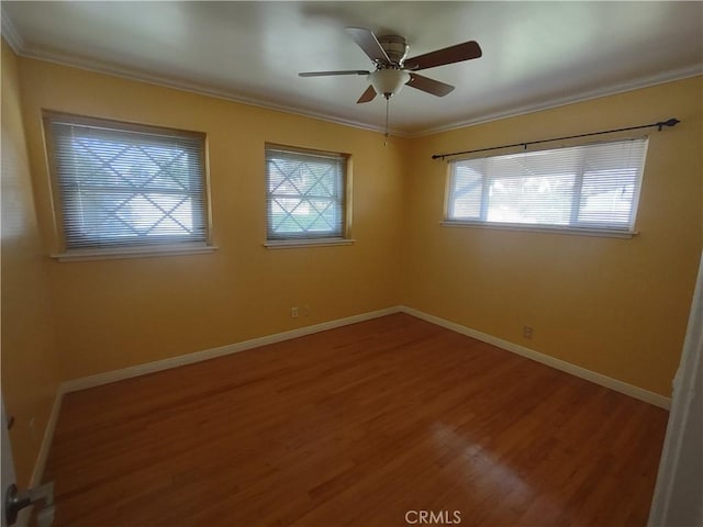 empty room featuring baseboards, wood finished floors, and crown molding