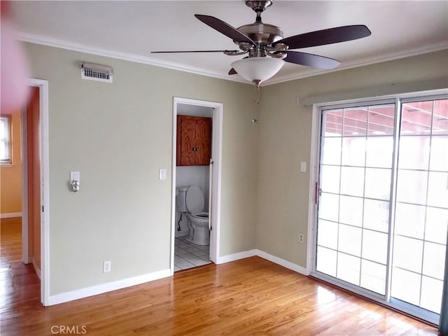 unfurnished room featuring a ceiling fan, visible vents, light wood-style flooring, and crown molding