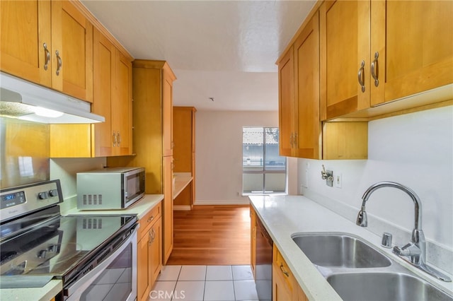 kitchen featuring light tile patterned floors, under cabinet range hood, appliances with stainless steel finishes, light countertops, and a sink