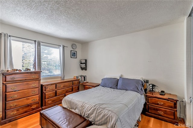 bedroom with light wood-type flooring and a textured ceiling