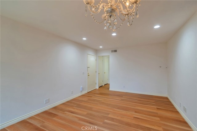 spare room with an inviting chandelier, light wood-style floors, recessed lighting, and baseboards